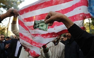 On the eve of renewed sanctions by Washington, Iranian protesters burn a dollar banknote and a US makeshift flag during a demonstration outside the former US embassy in the Iranian capital Tehran on November 4, 2018, marking the anniversary of its storming by student protesters that triggered a hostage crisis in 1979. (ATTA KENARE / AFP)