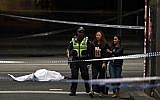A police officer directs people away from the crime scene as a body is seen covered with a white sheet in Melbourne on November 9, 2018 (Photo by WILLIAM WEST / AFP)