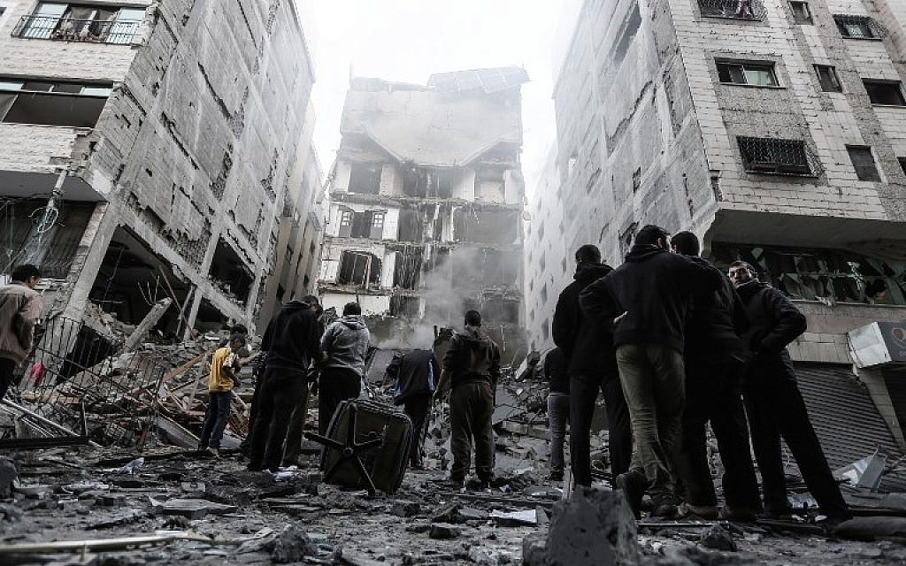 People look at the rubble of a building in Gaza City on November 13, 2018, after an Israeli air strike.  (MAHMUD HAMS / AFP)