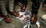 Palestinians step on a burnt image of Defense Minister Avigdor Lieberman in front of the house Hamas chief Ismail Haniyeh's home in Gaza on November 14, 2018. (Mahmud Hams/AFP)
