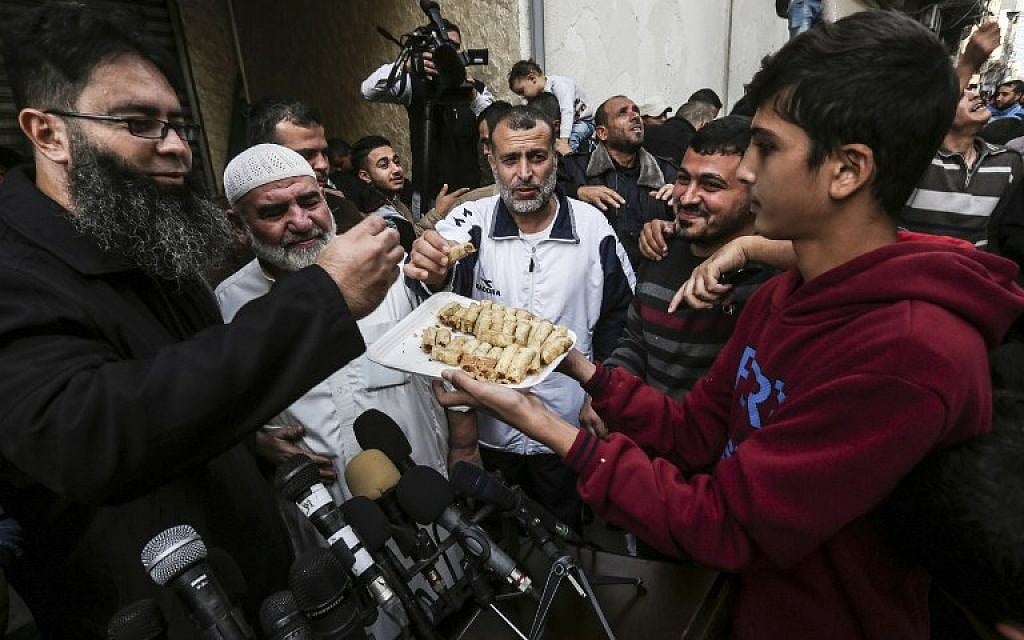 A Palestinian passes out sweets during a gathering in front of Hamas chief Ismail Haniyeh's home in Gaza on November 14, 2018. (Mahmud Hams/AFP)