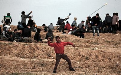 A Palestinian demonstrator uses a slingshot to throw stones towards Israeli forces during a protest on November 16, 2018, on the eastern outskirts of Gaza City, near the border with Israel. (Mahmud Hams/AFP)