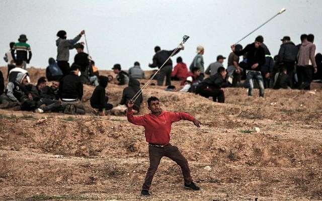 A Palestinian demonstrator uses a slingshot to throw stones towards Israeli forces during a protest on November 16, 2018, on the eastern outskirts of Gaza City, near the border with Israel. (Mahmud Hams/AFP) A Palestinian demonstrator uses a slingshot to throw stones towards Israeli forces during a protest on November 16, 2018, on the eastern outskirts of Gaza City, near the border with Israel. (Mahmud Hams/AFP)