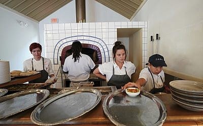 Chef de cuisine Cara Peterson, left, sous chef Julia Henner, second right, and line cook Naomi Martinez, right, work at the pita oven in Alon Shaya's restaurant Saba in New Orleans, August 23, 2018. (Gerald Herbert/AP)