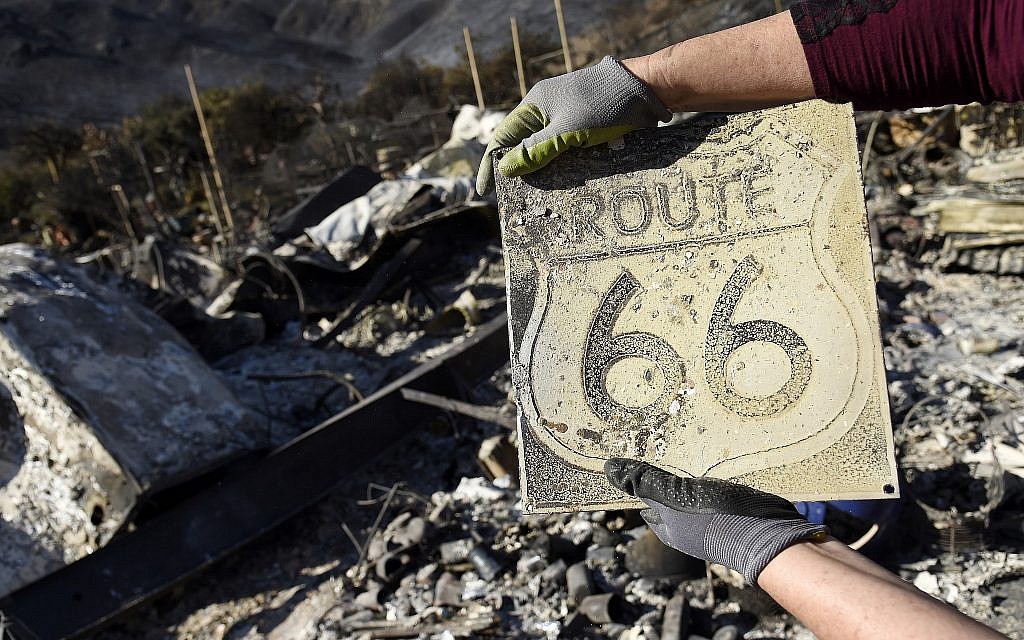 Donna Phillips shows a charred Route 66 sign she found among the possessions of her friend Marsha Maus, Sunday, November 11, 2018, after wildfires tore through the Seminole Springs Mobile Home Park in Agoura Hills, Calif. Maus has been a resident of the neighborhood for 15 years. (AP Photo/Chris Pizzello)