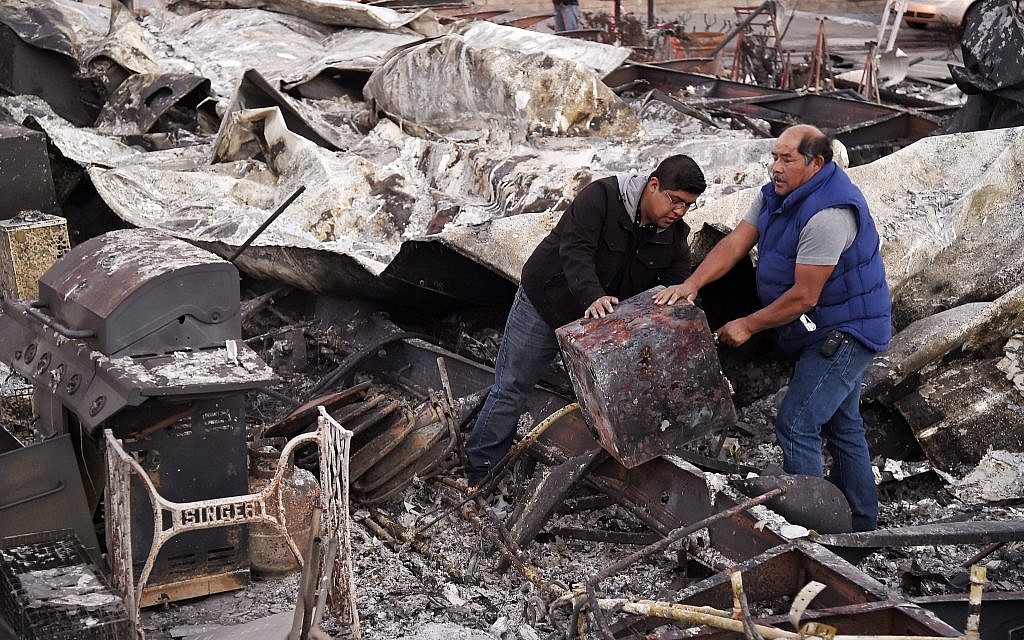 Santos Alvarado, right, and his son Ricky recover a safe deposit box from their destroyed home at Seminole Springs Mobile Home Park, November 11, 2018, following devastating wildfires in the area in Agoura Hills, California. (AP Photo/Chris Pizzello)