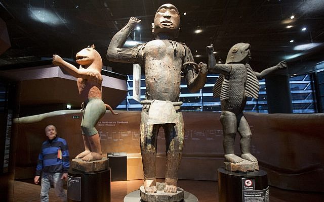 Visitors look at wooden royal statues of the Dahomey kingdom, dated 19th century, today's Benin, at Quai Branly museum in Paris, France, Friday, Nov. 23, 2018 (AP/Michel Euler)