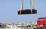 In this October 12, 2013 file photo, the casket of one of the migrants who died when their boat capsized off in the Canal of Sicily is lifted by crane to an Italian Navy ship at the Lampedusa island harbor. (AP Photo/Mauro Buccarello)