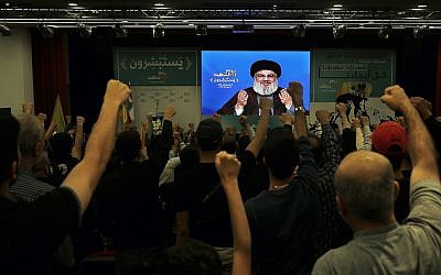 Supporters of the Hezbollah terror group raise their fists and cheer as they listen to a speech by Hezbollah leader Hassan Nasrallah, via a video link, during a rally marking Hezbollah Martyr's Day in Beirut, Lebanon, November 10, 2018. (AP/Bilal Hussein)