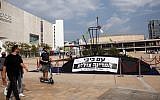 Israelis look at a submarine-like structure with a protest sign that reads, "With Bibi [Netanyahu], the country is sinking," at Habima Square in Tel Aviv, November 10, 2018. (Miriam Alster/Flash90)