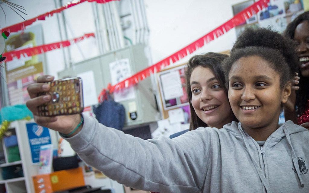 12-year old Sylvana Tsegai, right, taking a selfie at a Christmas party organized by the Kuchinate collective, in south Tel Aviv, January 9, 2018. (Miriam Alster/Flash90)
