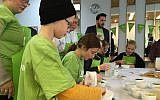 Jakob, 9, prepares purple icing to decorate Christmas cookies for a soup kitchen at Mitzvah Day at the Dueppel Youth Center in Berlin, November 18, 2018. (Toby Axelrod/ Times of Israel)