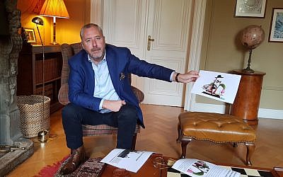 Mischael Modrikamen at his home near Brussels holds up an anti-Semitic caricature favored by anti-Israel circles in Belgium, Oct. 26, 2018. (Cnaan Liphshiz)