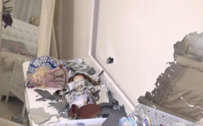 Dolls on a dresser just below a hole caused by shrapnel from a rocket in the wall of a bedroom in a home in Netivot, November 12, 2018 (Hadashot TV news)