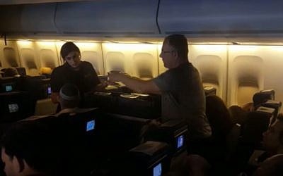 A flight attendant speaking to a passenger on an El Al flight from New York to Israel on November 16, 2018. (screen capture: Israel Hayom)
