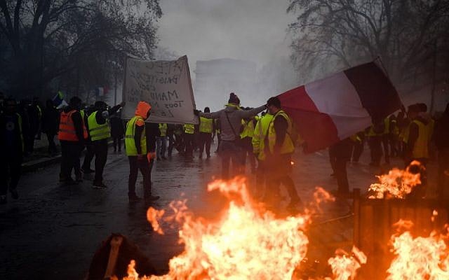 Demonstrators carry a French flag during a protest of Yellow vests (Gilets jaunes) against rising oil prices and living costs, on December 1, 2018 in Paris (Photo by Alain JOCARD / AFP) Demonstrators carry a French flag during a protest of Yellow vests (Gilets jaunes) against rising oil prices and living costs, on December 1, 2018 in Paris (Photo by Alain JOCARD / AFP)