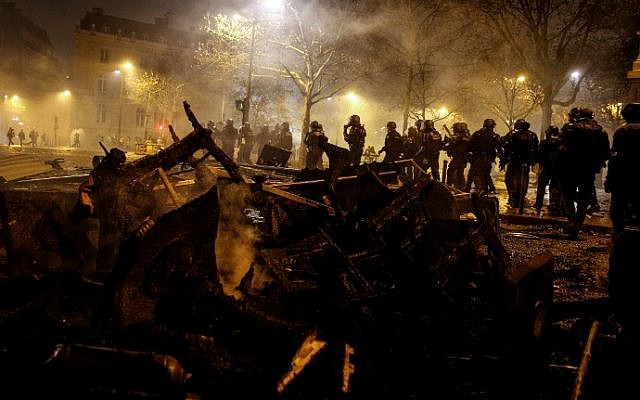 Riot police walk past burnt chairs and tables, during a protest of Yellow vests (Gilets jaunes) against rising oil prices and living costs, on the Champs Elysees avenue in Paris on December 1, 2018 (Photo by Geoffroy VAN DER HASSELT / AFP)