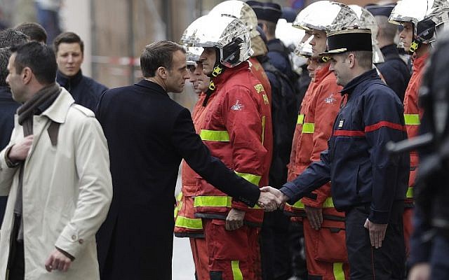 French President Emmanuel Macron, left, shakes hands with a firefighter during a visit in Paris on December 2, 2018, a day after clashes at a protest of "yellow vests" (gilets jaunes) against rising oil prices and living costs. (Geoffroy Van Der Hasselt/AFP)