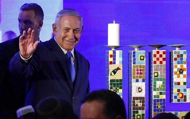 Prime Minister Benjamin Netanyahu waves before lighting a stylized-candle during the start of Hanukkah, the Jewish festival of lights, in Ramat Gan in the suburbs of the Mediterranean coastal city of Tel Aviv on December 2, 2018. (Jack GUEZ / AFP) Prime Minister Benjamin Netanyahu waves before lighting a stylized-candle during the start of Hanukkah, the Jewish festival of lights, in Ramat Gan in the suburbs of the Mediterranean coastal city of Tel Aviv on December 2, 2018. (Jack GUEZ / AFP)