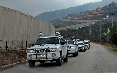 United Nations Interim Forces in Lebanon (UNIFIL) military police cars drive past a concrete separation barrier between the southern Lebanese village of Kfar Kila and Israel on the border between the two countries on December 4, 2018 (Ali Dia/AFP)