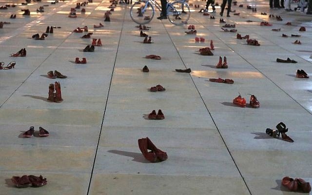 Israelis walk past an installation of red shoes during a rally against domestic violence in Tel Aviv on December 4, 2018. (JACK GUEZ / AFP)