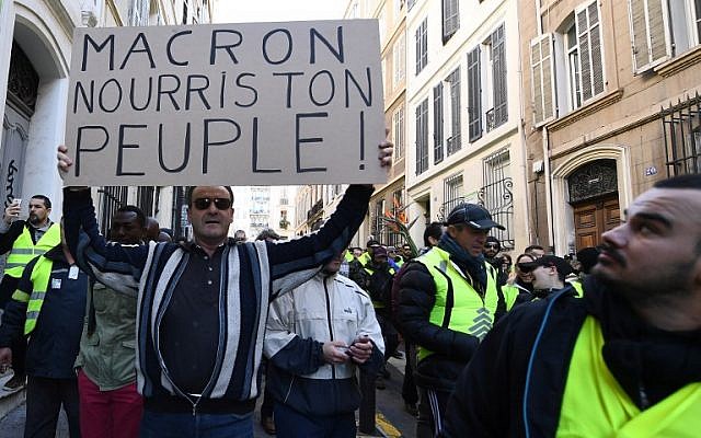 A man holds a sign reading "Macron feed your People" as protesters wearing "yellow vests" (gilets jaunes) demonstrate on December 8, 2018, in Marseille, southern France, during a protest against rising costs of living they blame on high taxes. (Boris Horvat/AFP)