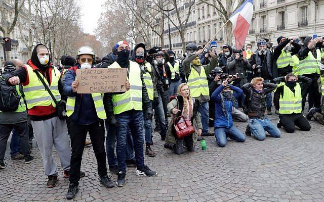 A protester holds a sign reading "Macron stop hiding" near the Champs Elysees avenue in Paris on December 8, 2018 during a "yellow vests" (gilets jaunes) demonstration protesting rising costs of living they blame on high taxes. (Thomas Samson/AFP)