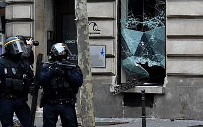 Riot police stand in front of a broken window during "yellow vest" protests near the Champs Elysees avenue in Paris on December 8, 2018. (Bertrand Guay/AFP)