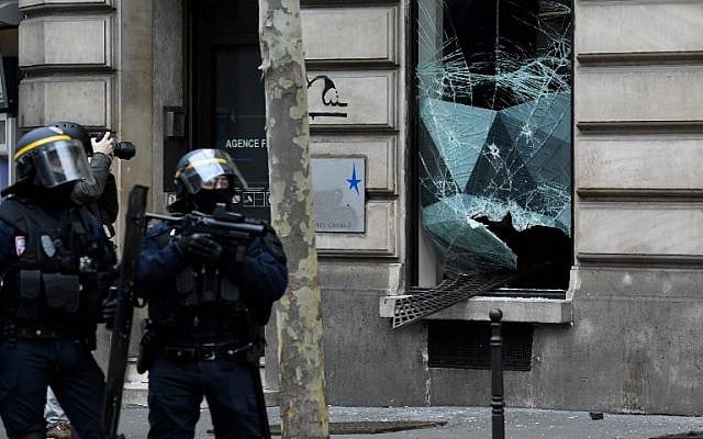 Riot police stand in front of a broken window during "yellow vest" protests near the Champs Elysees avenue in Paris on December 8, 2018. (Bertrand Guay/AFP)