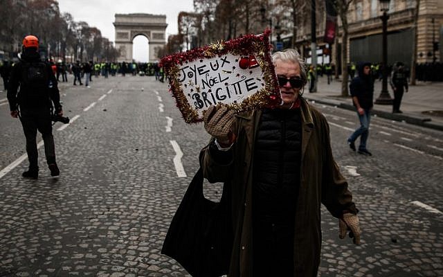 A protestor holds a sign reading "Merry Christmas Brigitte (Macron)" during a "yellow vests" (gilets jaunes) demonstration against the rising cost of living in front of the Arc de Triomphe in Paris on December 8, 2018. (Abdul Abeissa/AFP)