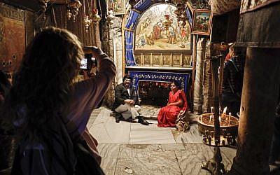A couple poses for a picture in front of the Grotto of the Nativity, the place where Jesus is said to have been born, inside the Church of the Nativity in the West Bank city of Bethlehem on December 12, 2018. (Thomas Coex/AFP)