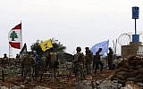 A picture taken from the southern Lebanese village of Meiss al-Jabal on December 16, 2018, shows Israeli soldiers watching as United Nations Interim Forces in Lebanon (UNIFIL) soldiers speak with Lebanese soldiers in front of a Hezbollah flag. (Mahmoud Zayyat/AFP)