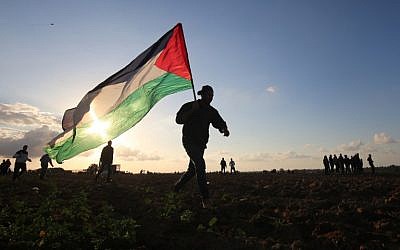 A Palestinian protester carries a national flag during a demonstration near the border between Israel and Khan Yunis in the southern Gaza Strip, on December 21, 2018. (Photo by SAID KHATIB / AFP)