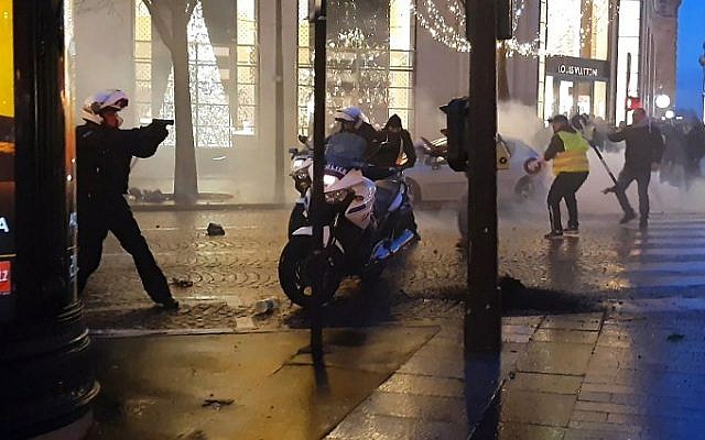 Screen capture from video shows a police biker, left, drawing his firearm as he and other police bikers are assaulted by protesters on the Champs-Elysees in Paris, December 22, 2018. (LINE PRESS/AFP) Screen capture from video shows a police biker, left, drawing his firearm as he and other police bikers are assaulted by protesters on the Champs-Elysees in Paris, December 22, 2018. (LINE PRESS/AFP)