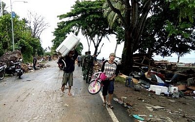 Residents evacuate from damaged homes on Carita beach, Indonesia, on December 23, 2018, after the area was hit by a tsunami on December 22 triggered by an eruption of the Anak Krakatoa volcano, which killed dozens and injured hundreds more as it slammed without warning into tourist beaches and coastal areas around Sunda Strait, sending panicked holiday makers and residents fleeing. (Semi/AFP)
