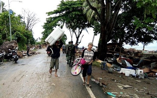 Residents evacuate from damaged homes on Carita beach, Indonesia, on December 23, 2018, after the area was hit by a tsunami on December 22 triggered by an eruption of the Anak Krakatoa volcano, which killed dozens and injured hundreds more as it slammed without warning into tourist beaches and coastal areas around Sunda Strait, sending panicked holiday makers and residents fleeing. (Semi/AFP) Residents evacuate from damaged homes on Carita beach, Indonesia, on December 23, 2018, after the area was hit by a tsunami on December 22 triggered by an eruption of the Anak Krakatoa volcano, which killed dozens and injured hundreds more as it slammed without warning into tourist beaches and coastal areas around Sunda Strait, sending panicked holiday makers and residents fleeing. (Semi/AFP)