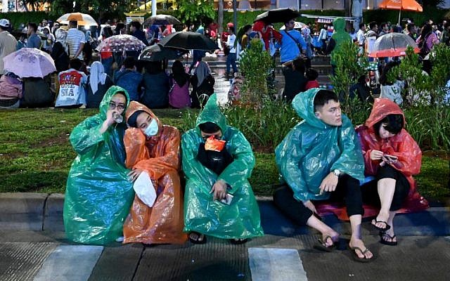 Indonesians brave the rain as they wait to welcome the New Year in central Jakarta on December 31, 2018. (GOH CHAI HIN / AFP)