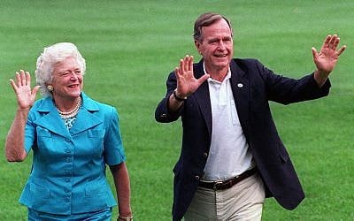 In this Aug. 24, 1992, file photo, President George H.W. Bush and first lady Barbara Bush walk with their dog Millie across the South Lawn as they return to the White House (AP Photo/Scott Applewhite, File)