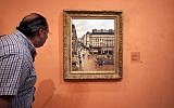 This May 12, 2005, file photo shows an unidentified visitor viewing the Impressionist painting called "Rue St.-Honore, Apres-Midi, Effet de Pluie" painted in 1897 by Camille Pissarro, on display in the Thyssen-Bornemisza Museum in Madrid. (AP Photo/Mariana Eliano, File)