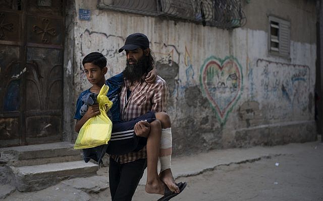 In this September 16, 2018, photo, Raed Abu Khader, right, carries his 12-year-old son Mohammed as they return from the hospital in Gaza City. Mohammed was shot in the leg at one of the demonstrations on Gaza's border with Israel. (AP Photo/Felipe Dana) In this September 16, 2018, photo, Raed Abu Khader, right, carries his 12-year-old son Mohammed as they return from the hospital in Gaza City. Mohammed was shot in the leg at one of the demonstrations on Gaza's border with Israel. (AP Photo/Felipe Dana)