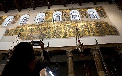 A visitor photographs a renovated part of a fresco inside the Church of the Nativity in the West Bank City of Bethlehem, December 6, 2018. (Majdi Mohammed/AP)