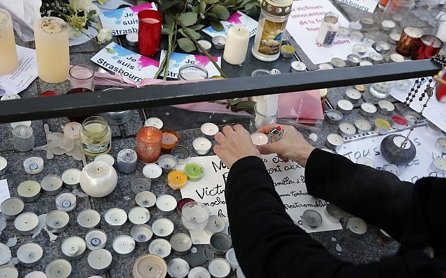 A woman lights a candle to pay respects to the victims of a deadly terror attack in Strasbourg, eastern France, two days after the attack, on Thursday, December 13, 2018. (AP Photo/Christophe Ena)