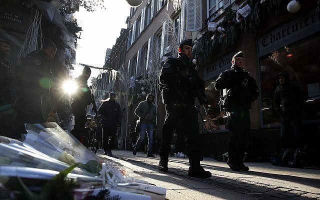 French police officers patrol in Strasbourg, France, in front of flowers commemorating the victims of a deadly December 11, 2018, terror attack, on Thursday, December 13, 2018. (AP Photo/Christophe Ena)