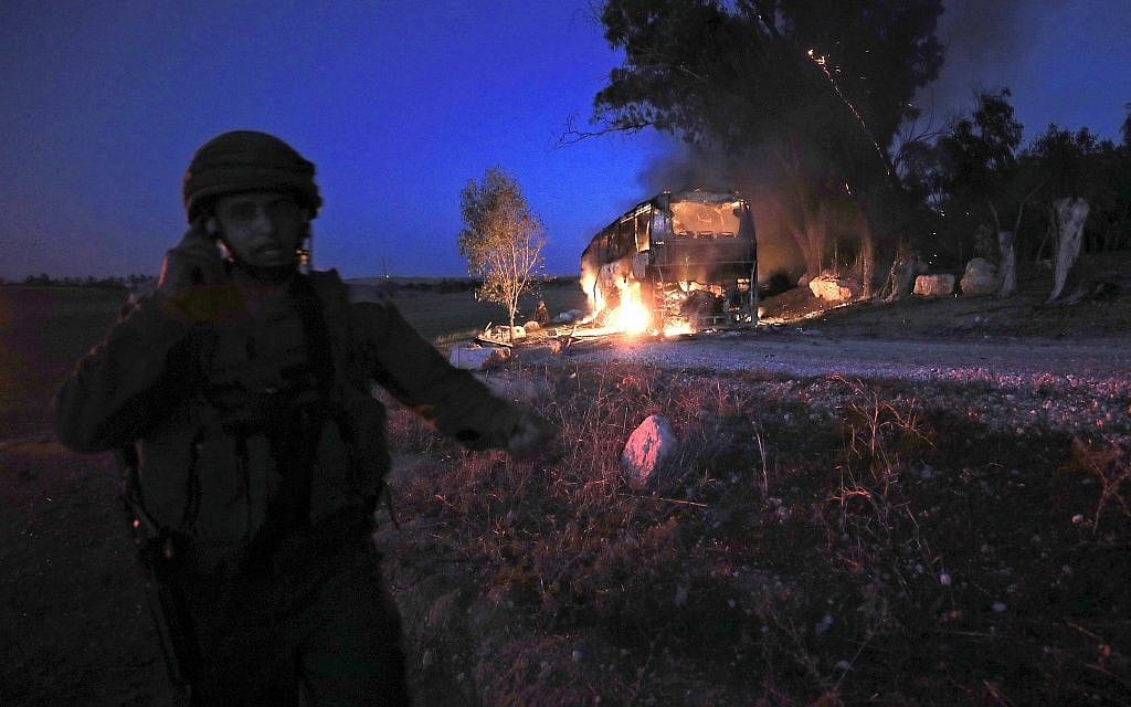 An Israeli soldier stands near a burning bus after it was hit by an anti-tank missilel fired from Gaza Strip near the Israel-Gaza border, Monday, November 12, 2018. (Tsafrir Abayov/AP) An Israeli soldier stands near a burning bus after it was hit by an anti-tank missilel fired from Gaza Strip near the Israel-Gaza border, Monday, November 12, 2018. (Tsafrir Abayov/AP)