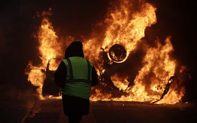 A demonstrator watches a burning car near the Champs-Elysees avenue during a demonstration, Dec.1, 2018 in Paris (AP Photo/Kamil Zihnioglu) A demonstrator watches a burning car near the Champs-Elysees avenue during a demonstration, Dec.1, 2018 in Paris (AP Photo/Kamil Zihnioglu)