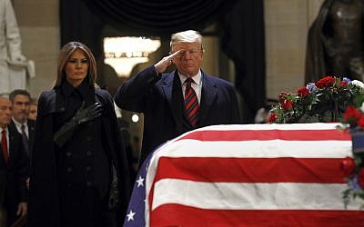 US President Donald Trump salutes alongside first lady Melania Trump in front of the flag-draped casket of former President George H.W. Bush in the Capitol Rotunda in Washington, Dec. 3, 2018. (AP Photo/Patrick Semansky)
