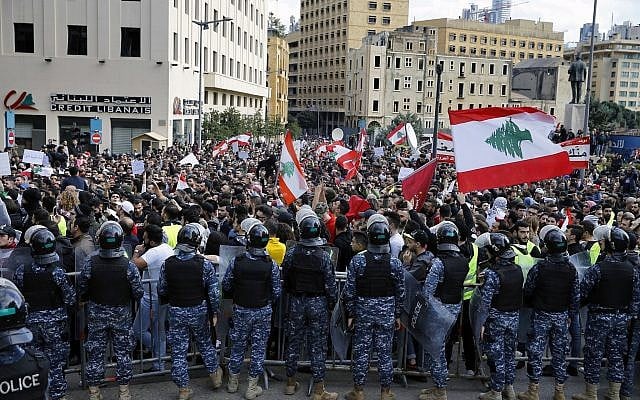 Anti-government protesters hold Lebanese flags and chant slogans as riot police stand guard in front of the government building, in central Beirut, Lebanon, Dec. 23, 2018 (AP Photo/Bilal Hussein) Anti-government protesters hold Lebanese flags and chant slogans as riot police stand guard in front of the government building, in central Beirut, Lebanon, Dec. 23, 2018 (AP Photo/Bilal Hussein)