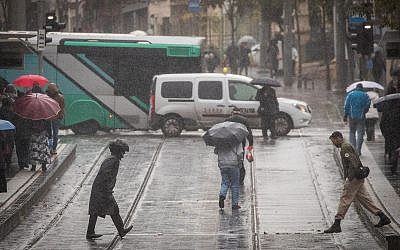 People walk on rain-soaked Jaffa Road in Jerusalem on December 6, 2018. (Yonatan Sindel/Flash90)
