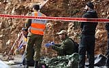 Israeli soldiers, medical officials and police inspect the scene of a terrorist shooting attack near Givat Assaf, in the central West Bank, on December 13, 2018. (Hadas Parush/Flash90)
