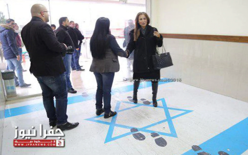 Jordan's minister for media affairs and communications and government spokesperson, Jumana Ghunaimat (R), stepping on the Israeli flag at the entrance to the trade union headquarters in Amman, December 2018. (Screen capture: Jamuna TV)